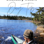 Man stands next to a green canoe at a Boundary Waters portage landing.