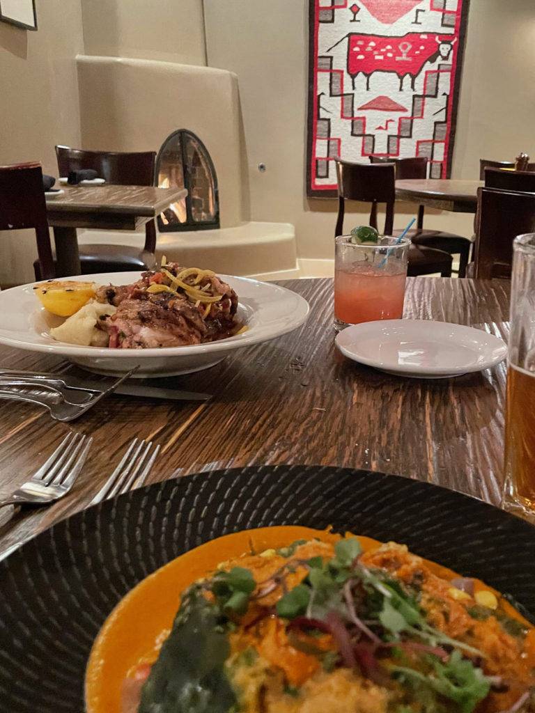 Two plates of food and an orange margarita at Rio Chama Steakhouse in Santa Fe