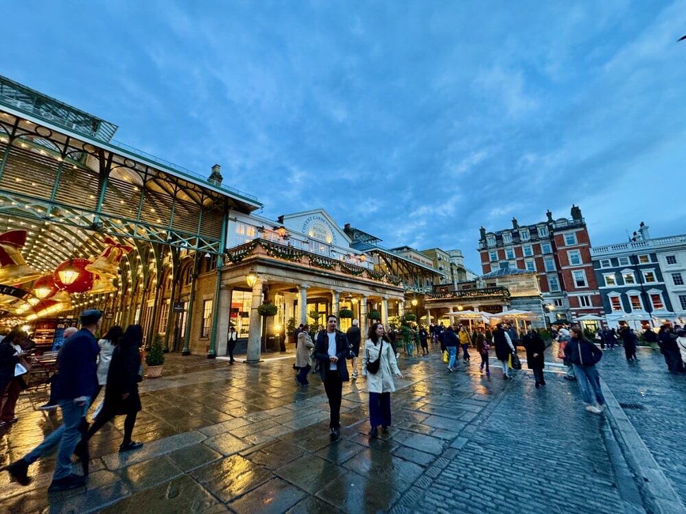 People mill about Covent Garden at nightfall in central London