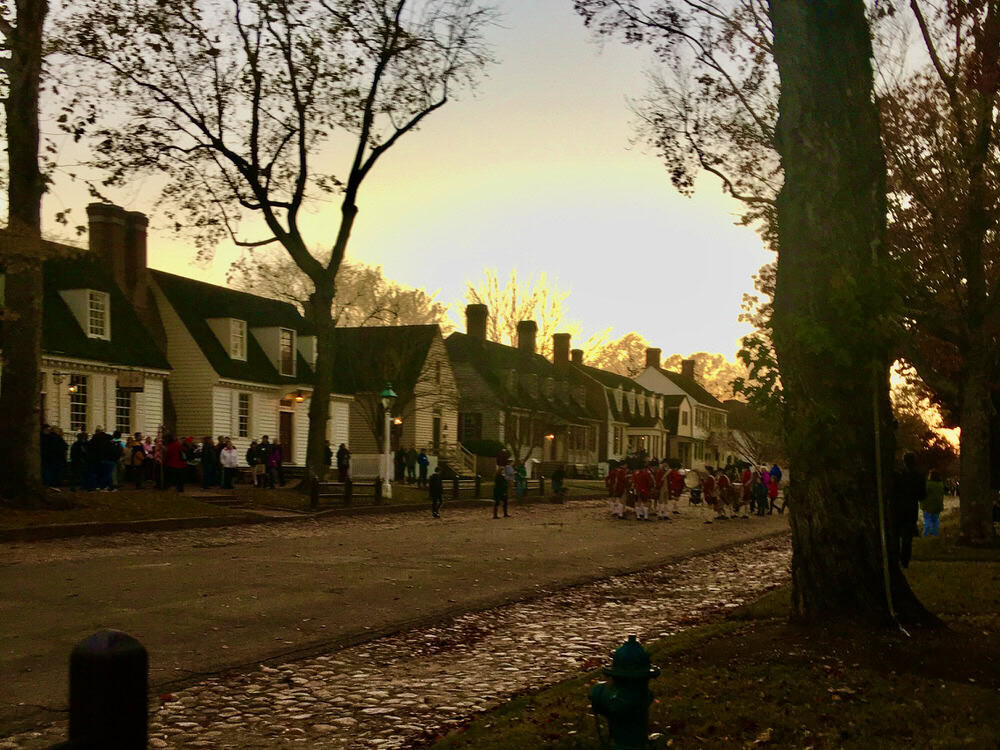 A fife and drum band marches down a colonial Virginia street