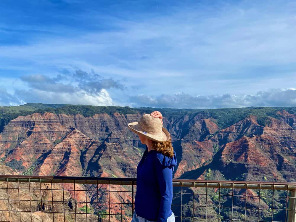 Woman looks towards a large canyon on Kauai