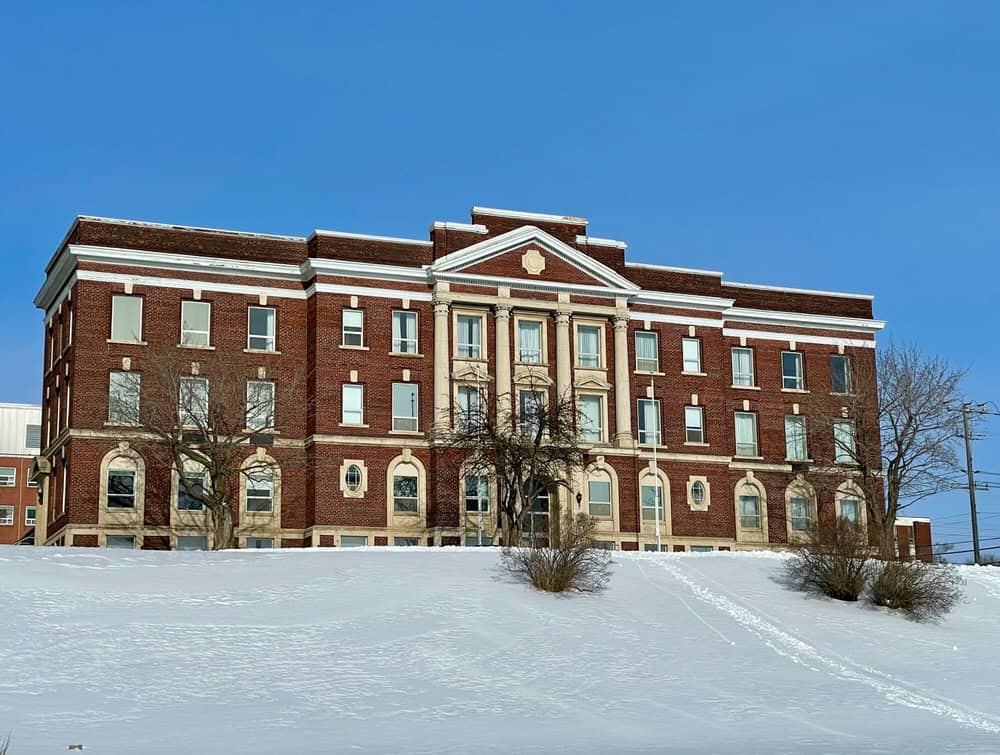 Large Victorian building at the top of a snowy hill