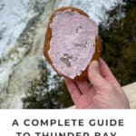 Hand holdng up a Persian donut in front of Kakabeka Falls in northwestern Ontario. Text reads "A Complete Guide to Thunder Bay, Ontario."