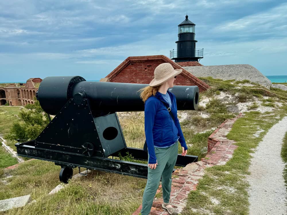 Woman stands in front of a cannon and lighthouse on Florida's Dry Tortugas