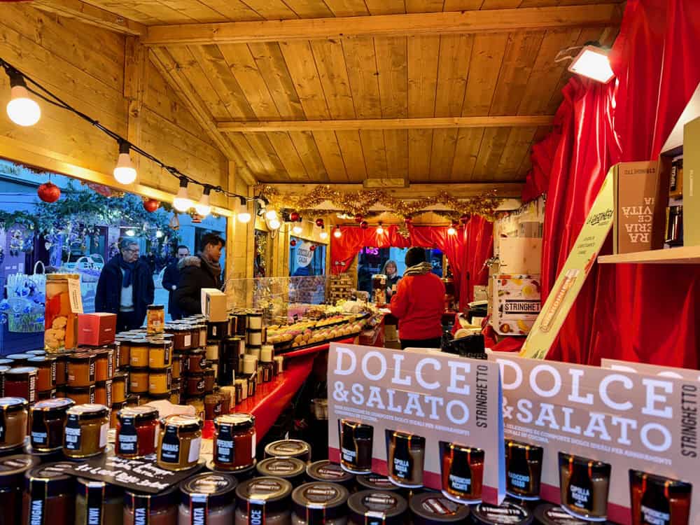 Stacks of jarred relishes and jams in a wooden Christmas market stand in Italy