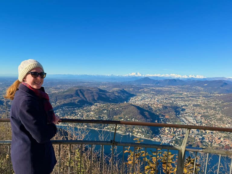 Woman stands at overlook near Brunate Italy looking towards the Swiss Alps