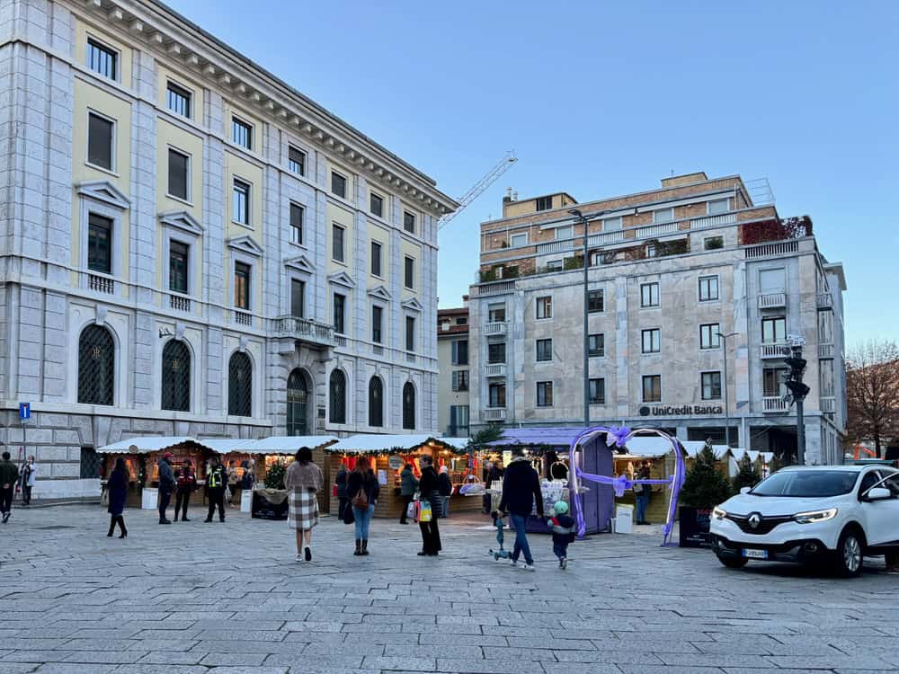 People walk towards a small collection of Christmas market stalls in Como City Italy