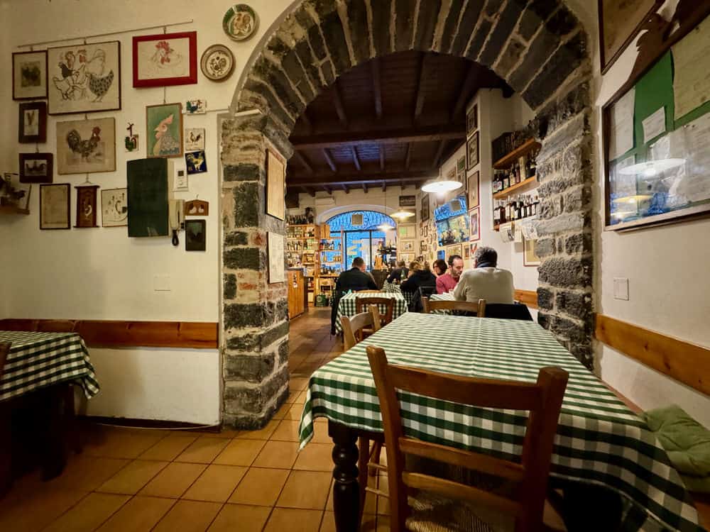 A small dining room with tables covered with green checkered tablecloths in Italy