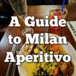 Plate of Italian buffet food with drinks. Text reads "A Guide to Milan Aperitivo"