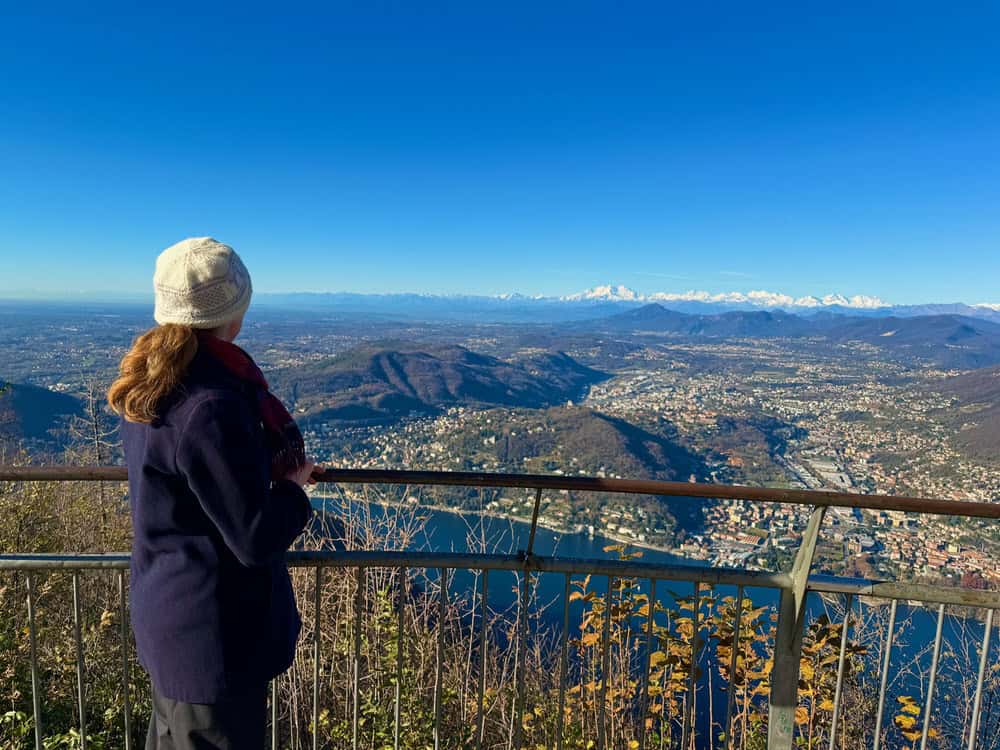 Woman stands overlooking Lake Como and the Swiss Alps from Faro Voltiano