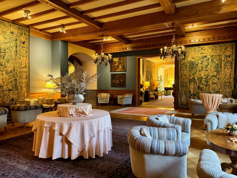 Tapestry covered banquet room with arm chairs, tables, and chandeliers in Grand Hotel Villa Castagnola Lugano Switzerland