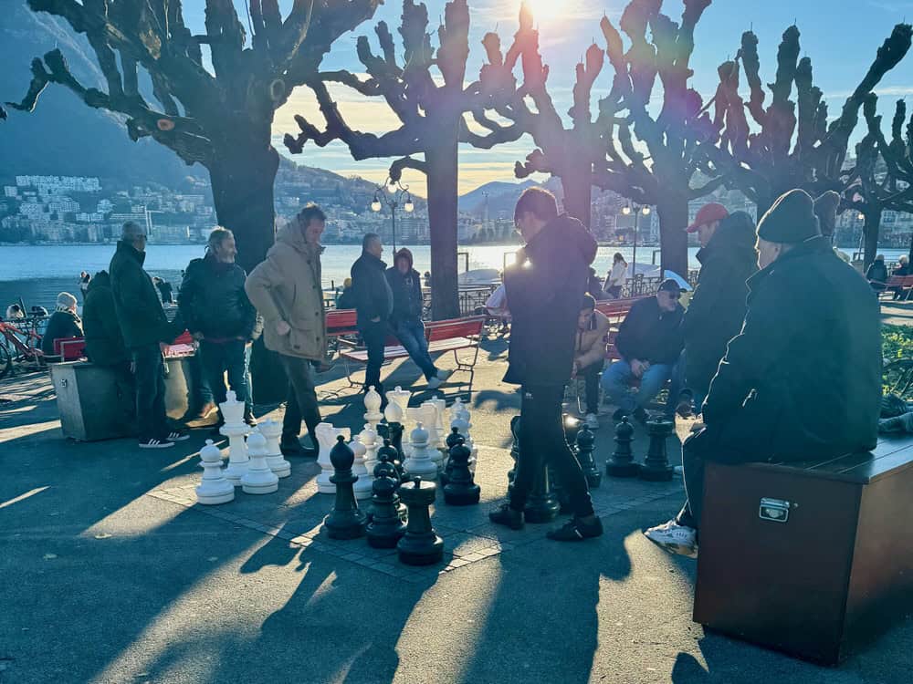 Chess players stand around a large outdoor game