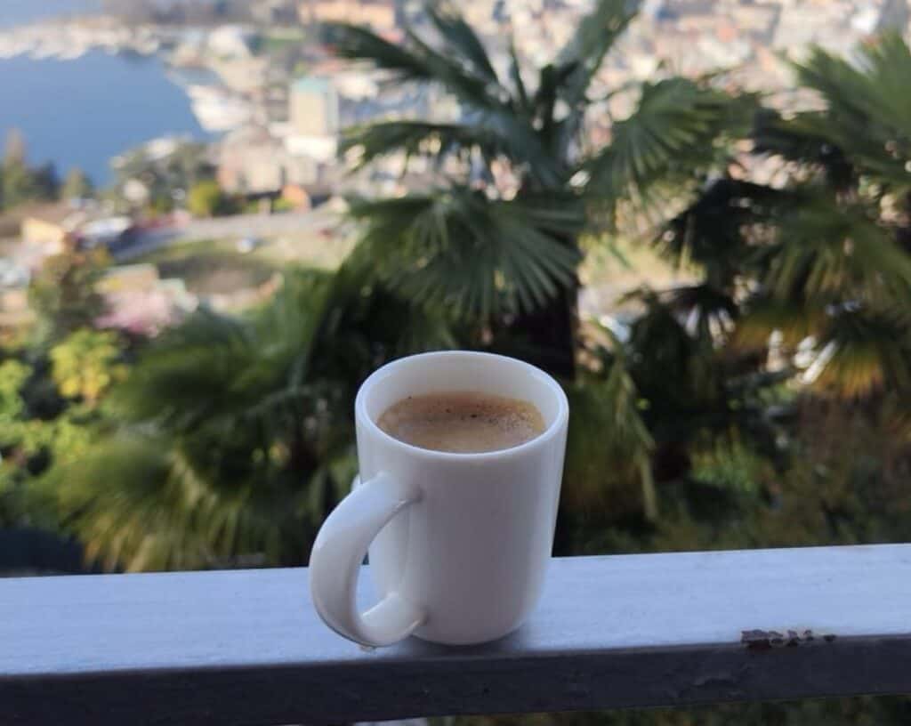 White handled espresso mug perched on a railing in the Ticino region of Switzerland