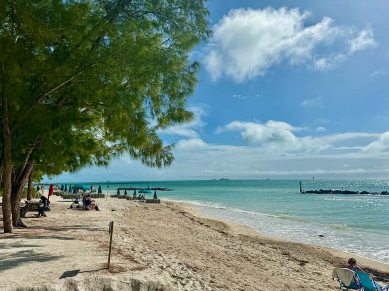 People sit on a beach on a partly sunny day in Key West, Florida's Fort Zachary Taylor State Park