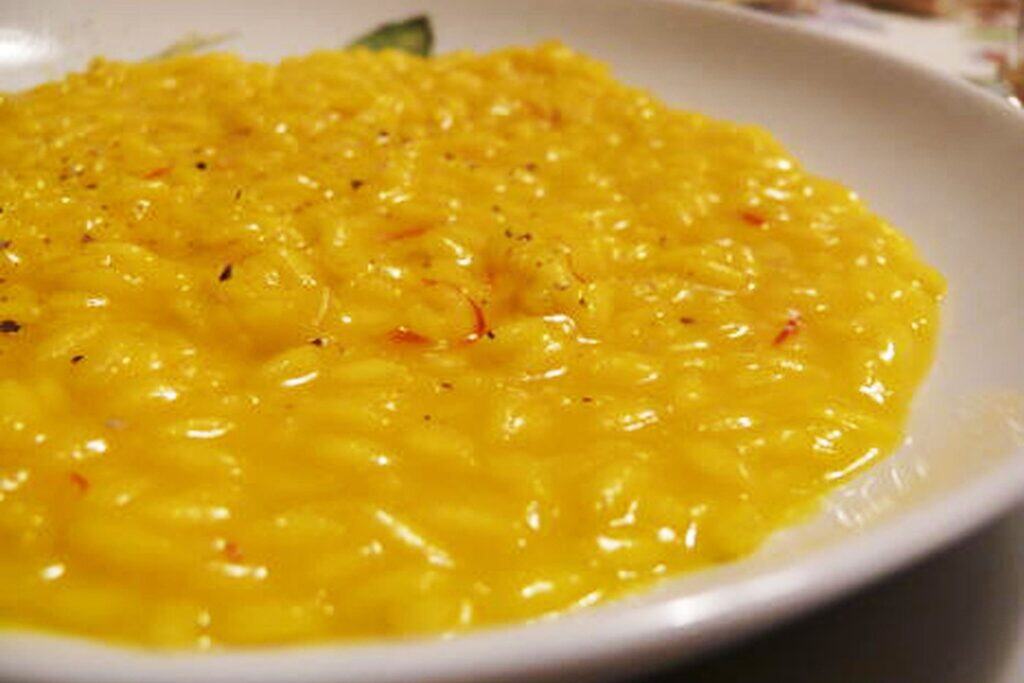 Plate of yellow risotto alla Milanese, a rice dish flavored and colored with saffron.