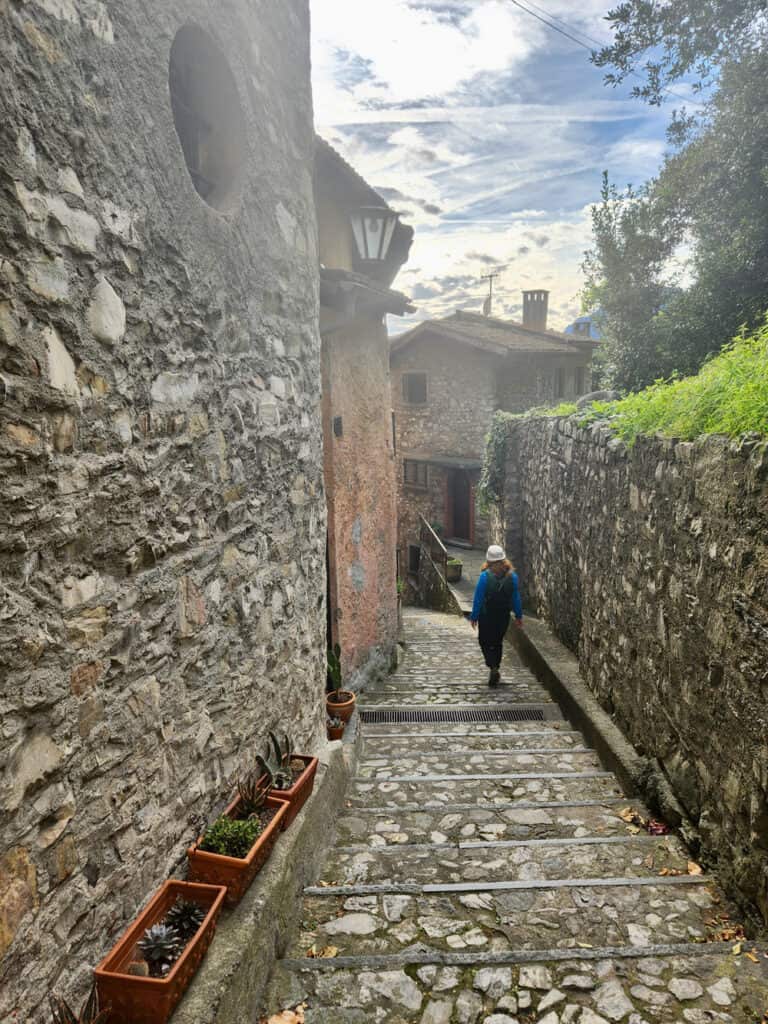 Woman in hiking gear walks through the stone streets of a medieval Swiss town
