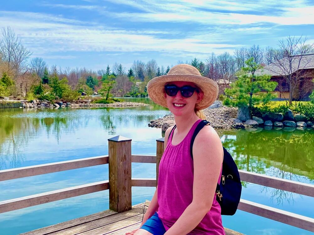 Woman in summer apparel sits on a dock beside the pond in the Japanese garden of Frederik Meijer Gardens in Grand Rapids, MI