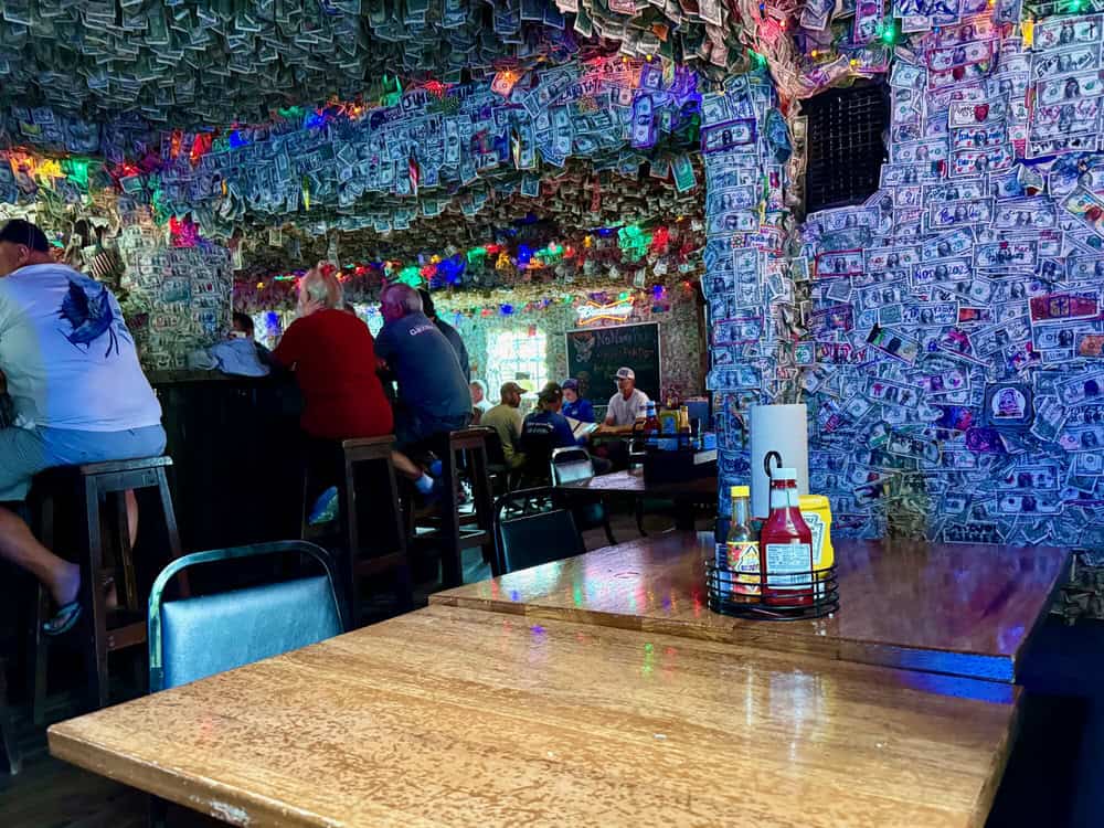People sit around a bar in a Florida Keys restaurant with dollar bill covered walls