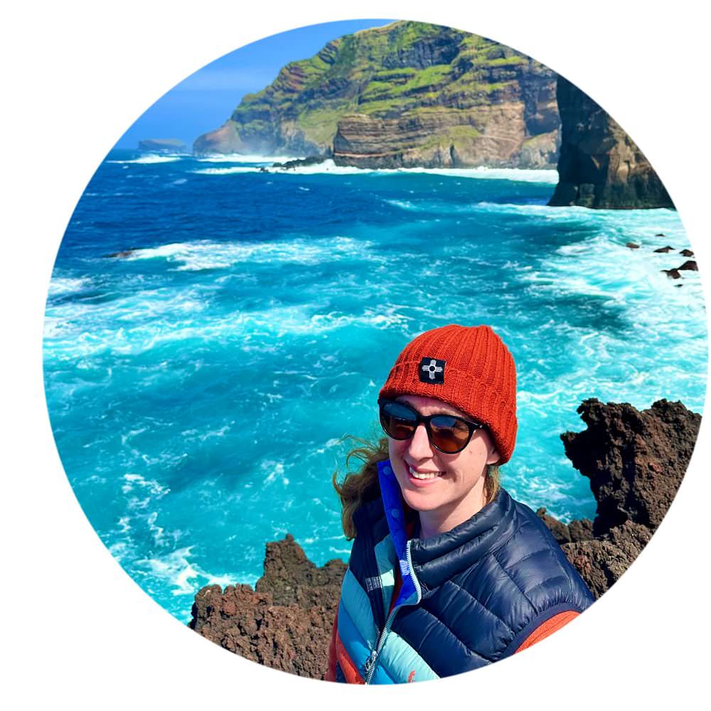 Woman stands in front of the churning Atlantic Ocean in the Portugal Azores on a basalt outcropping.