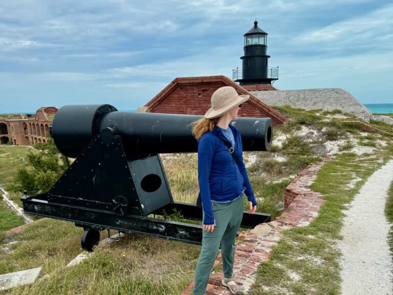 Woman stands in front of a black cannon on top of Fort Jefferson at Dry Tortugas National Park in Florida