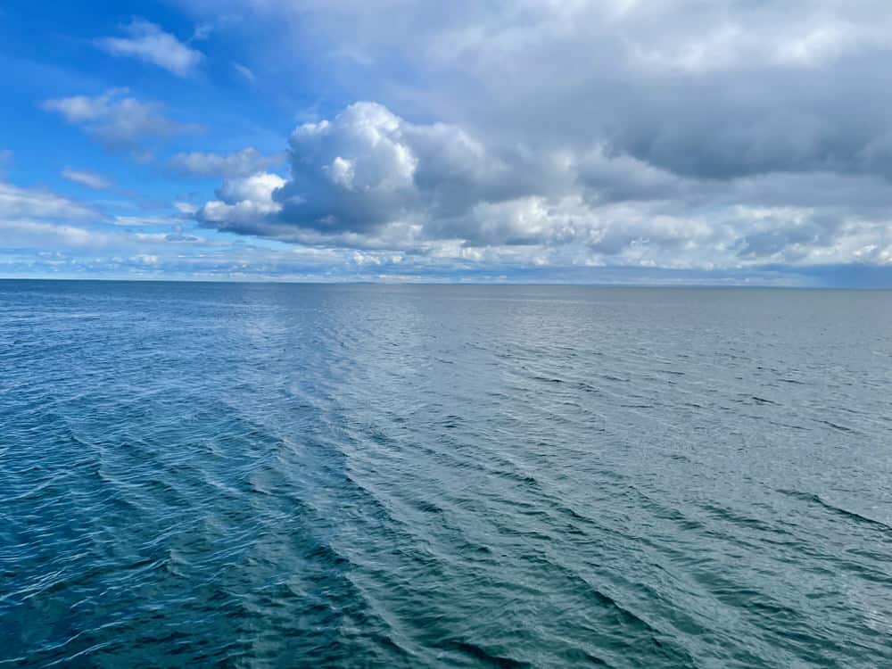 Puffy cumulus clouds over a rippling lake