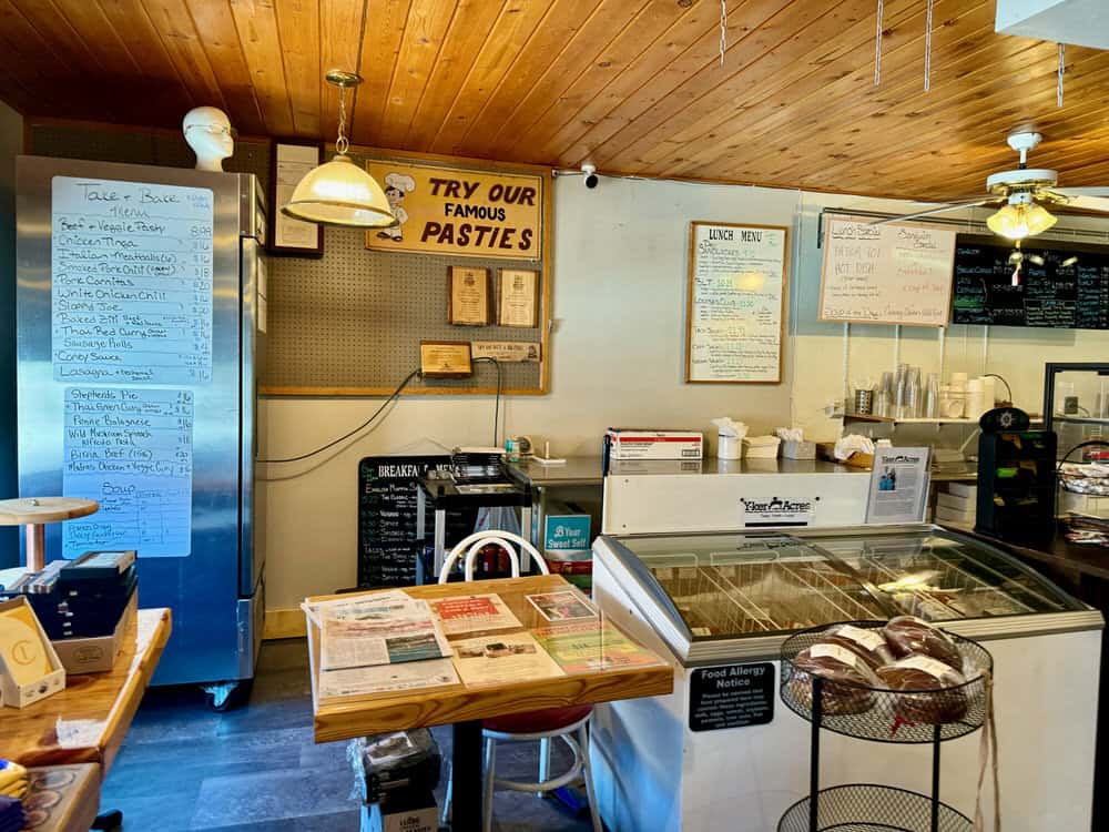 The interior of a small cafe with tables, fridges and a service counter