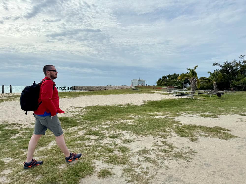 Man wearing a backpack walks through the sand on Garden Key at Dry Tortugas National Park
