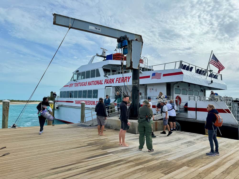 People stand on the dock at Dry Tortugas National Park in front of Yankee Freedom III ferry