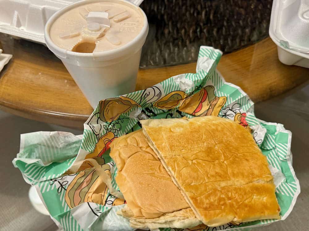 Cuban toast on a paper wrapper and a Cuban coffee