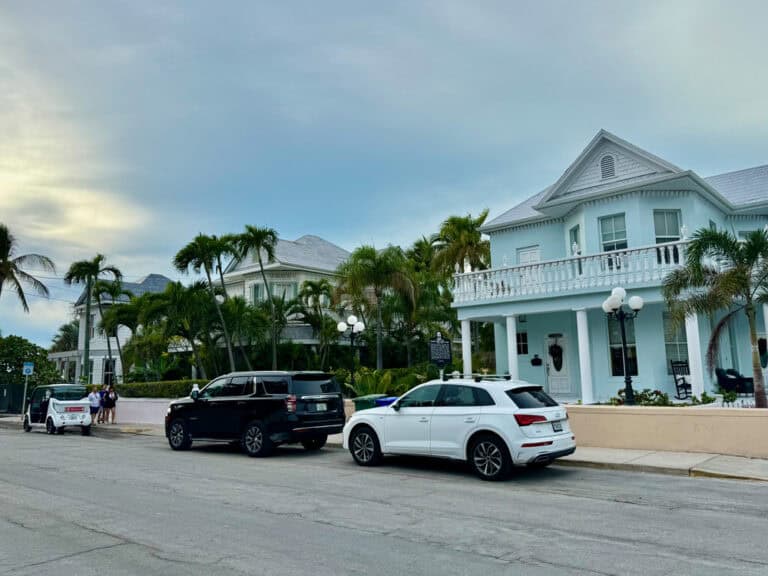 Cars and a golf cart parked in front of a Key West sidewalk