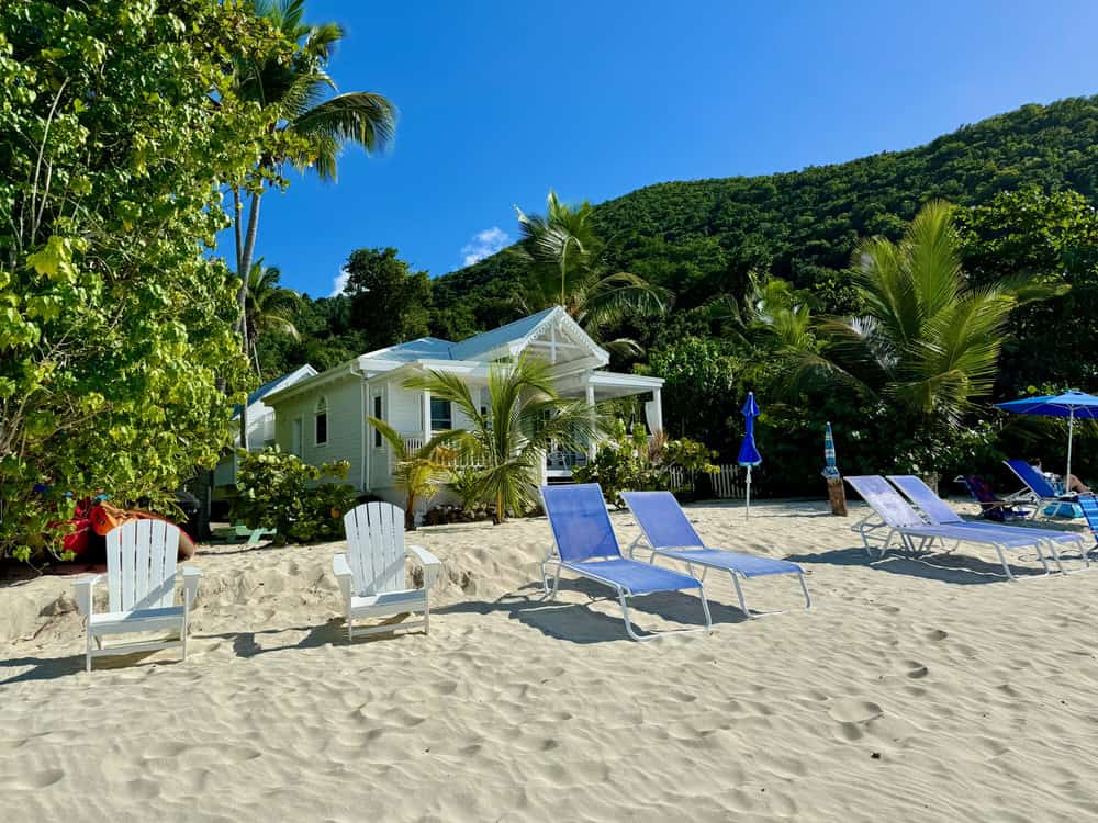 Beach chairs in front of a white beach cottage on a white sand beach on St. John US Virgin Islands