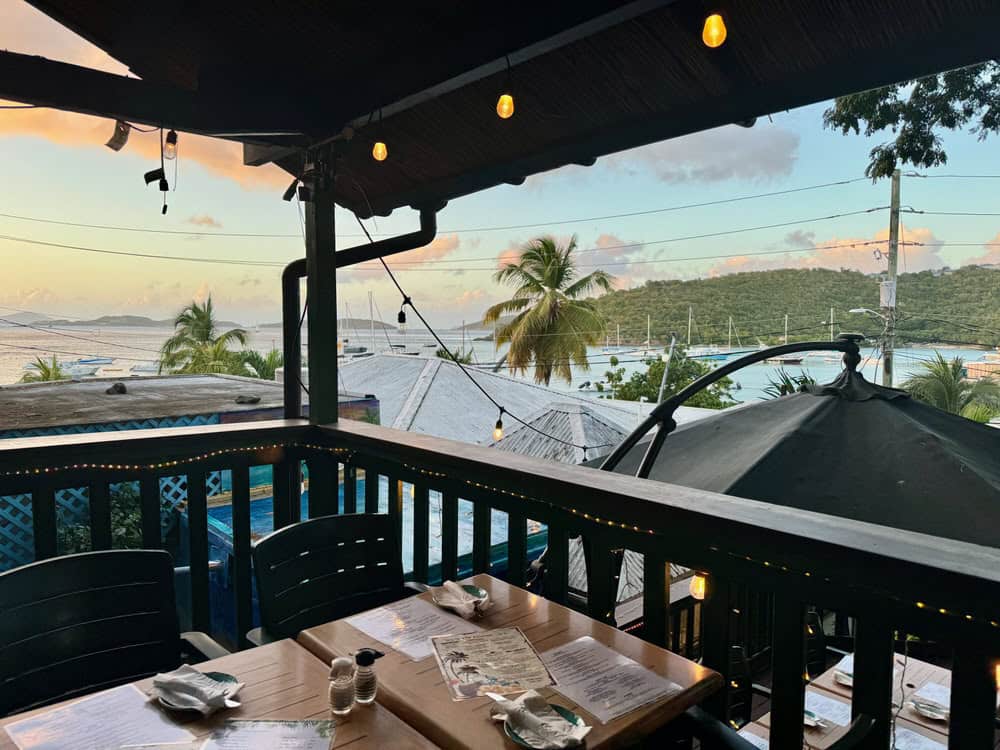 A table set up for restaurant guests on a patio overlooking Cruz Bay and neighboring Virgin Islands in the Caribbean.