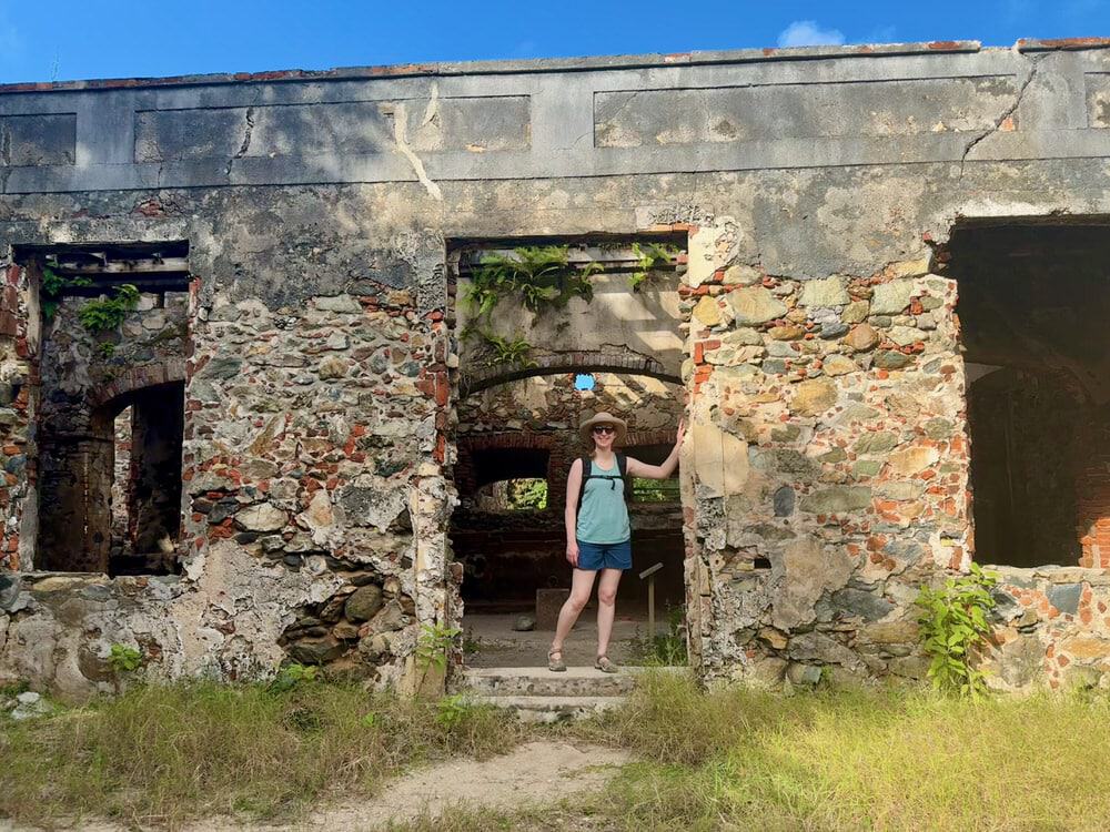 Woman stands in the doorway of an abandoned stone rum distillery on St. John island