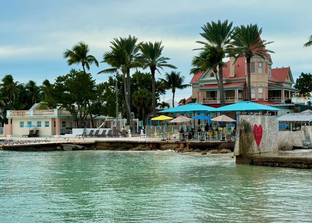 Look back at Southernmost Resort in Key West Florida with palm trees and beach infrastructure from a pier.