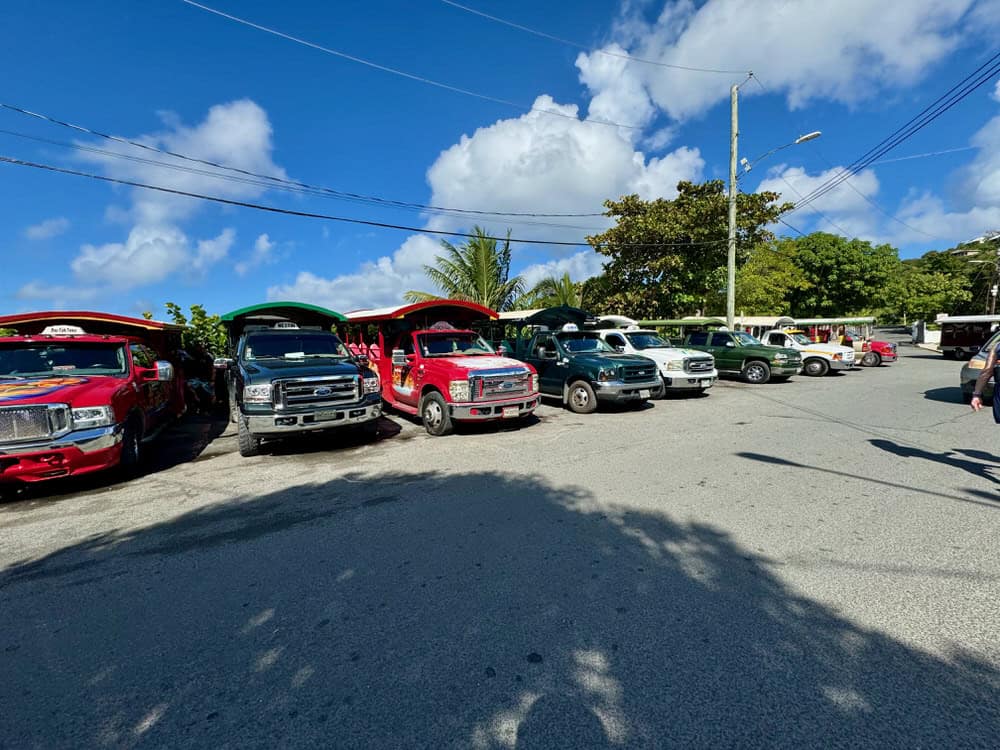 Pick up trucks with open air passenger benches in back wait for passengers in downtown Cruz Bay USVI