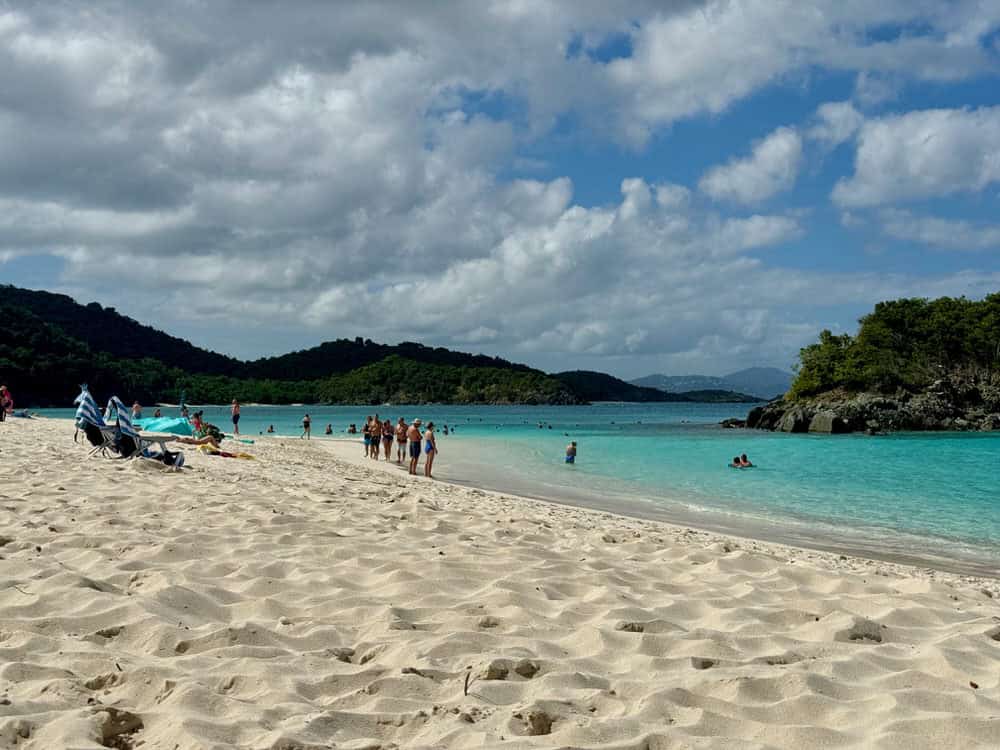 People stand and lounge on the white sand of Truck Bay Beach in St. John USVI.