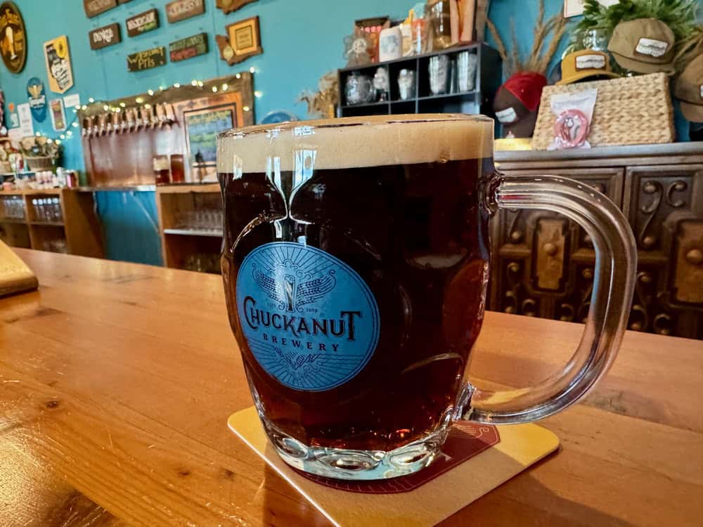 A glass mug filled with dark beer sits on a wooden bar at Chuckanut Brewery South Nut Taproom.