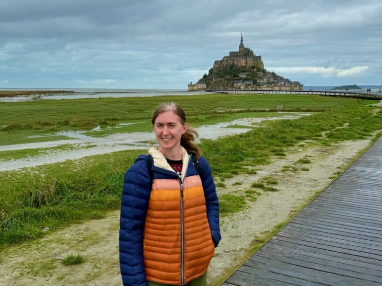 Woman stands on the walkway in front of Mt. St. Michel abbey in Normandy, France
