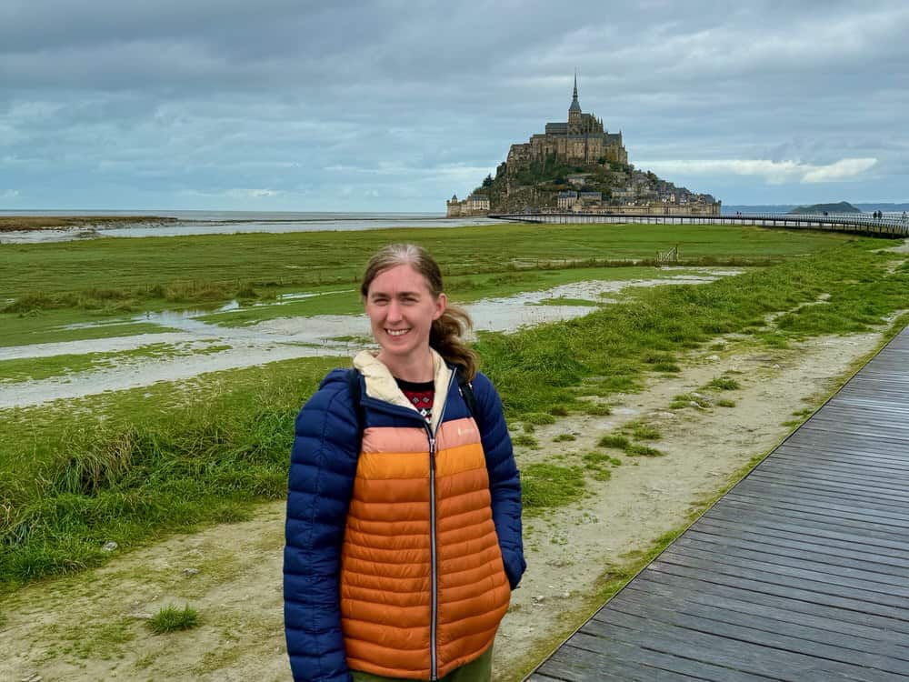 Woman stands on the walkway in front of Mt. St. Michel abbey in Normandy, France