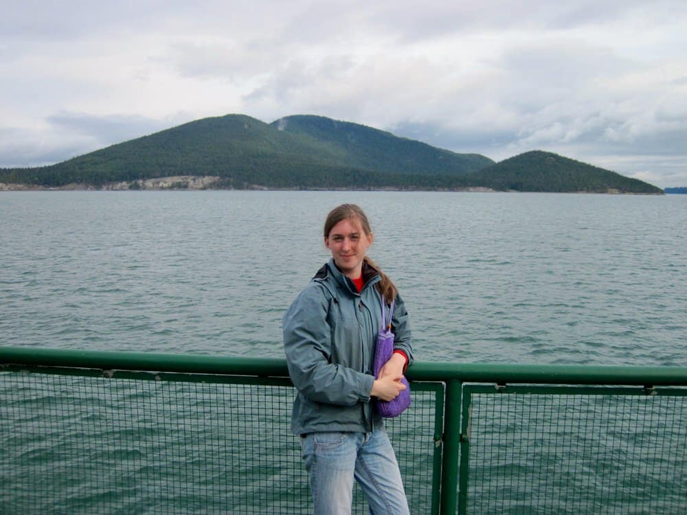 Young woman stands on the deck of Washington State Ferry sailing to the San Juan Islands