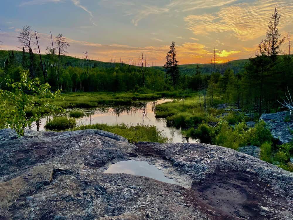 Sun sets over a small pond and rock outcropping in the northern Minnesota wilderness.
