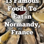 A platter of oysters with lemon wedges and a raspberry vinegarette. Text overlay reads "13 Famous Foods To Eat in Normandy France."