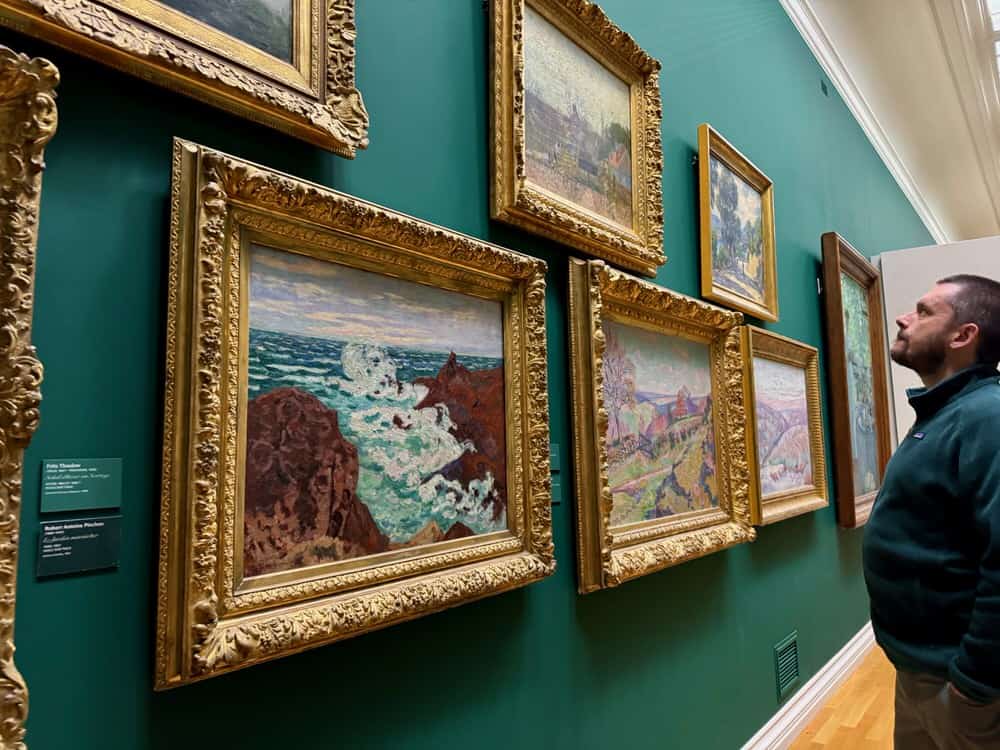A man looks at framed impressionism artwork in Rouen's Musee des Beaux-Arts