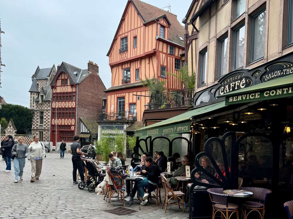 People sit at and pass by a cafe in Rouen's Old Town