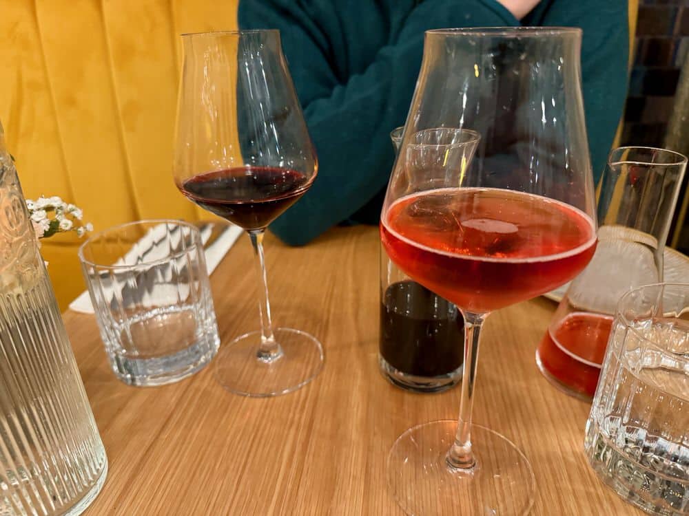 Two wine glasses filled with red wine and rose cider on a restaurant table
