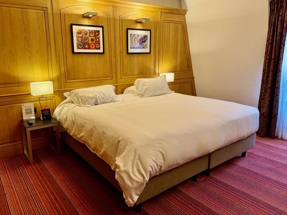King bed in a wood paneled room in Hotel de Bourgtheroulde Rouen France
