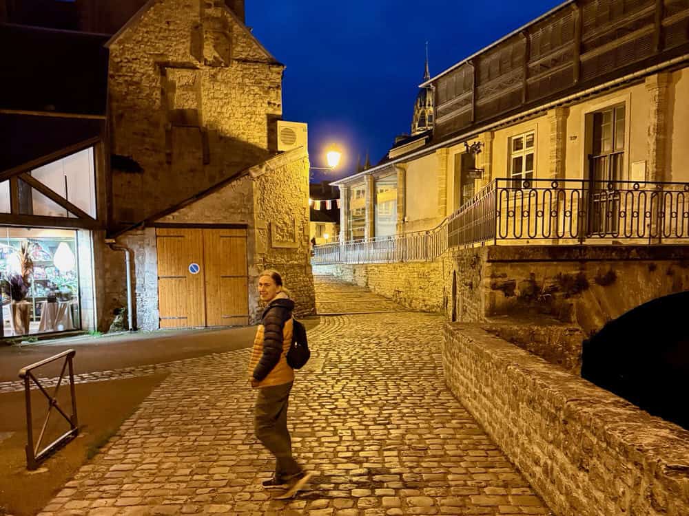 Woman walks on cobblestone streets after dark