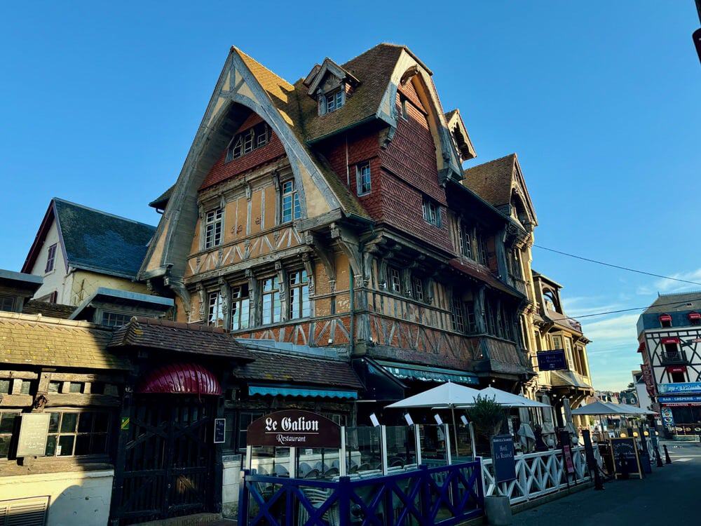 A tall half timbered building with restaurant tables set up outside