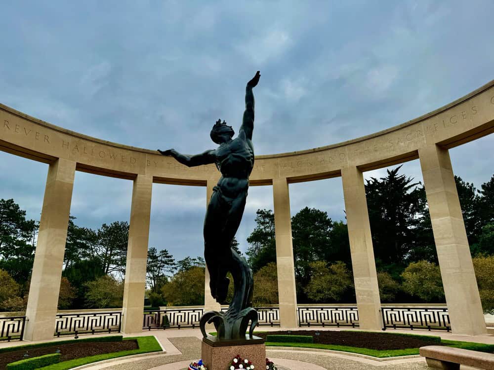 Bronze statue of a young man in the center of a stone memorial