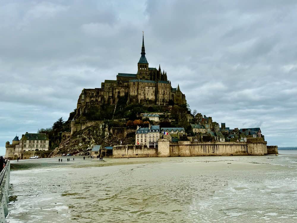 A medieval abbey rises from the top of a small tidal island surrounded by ramparts.
